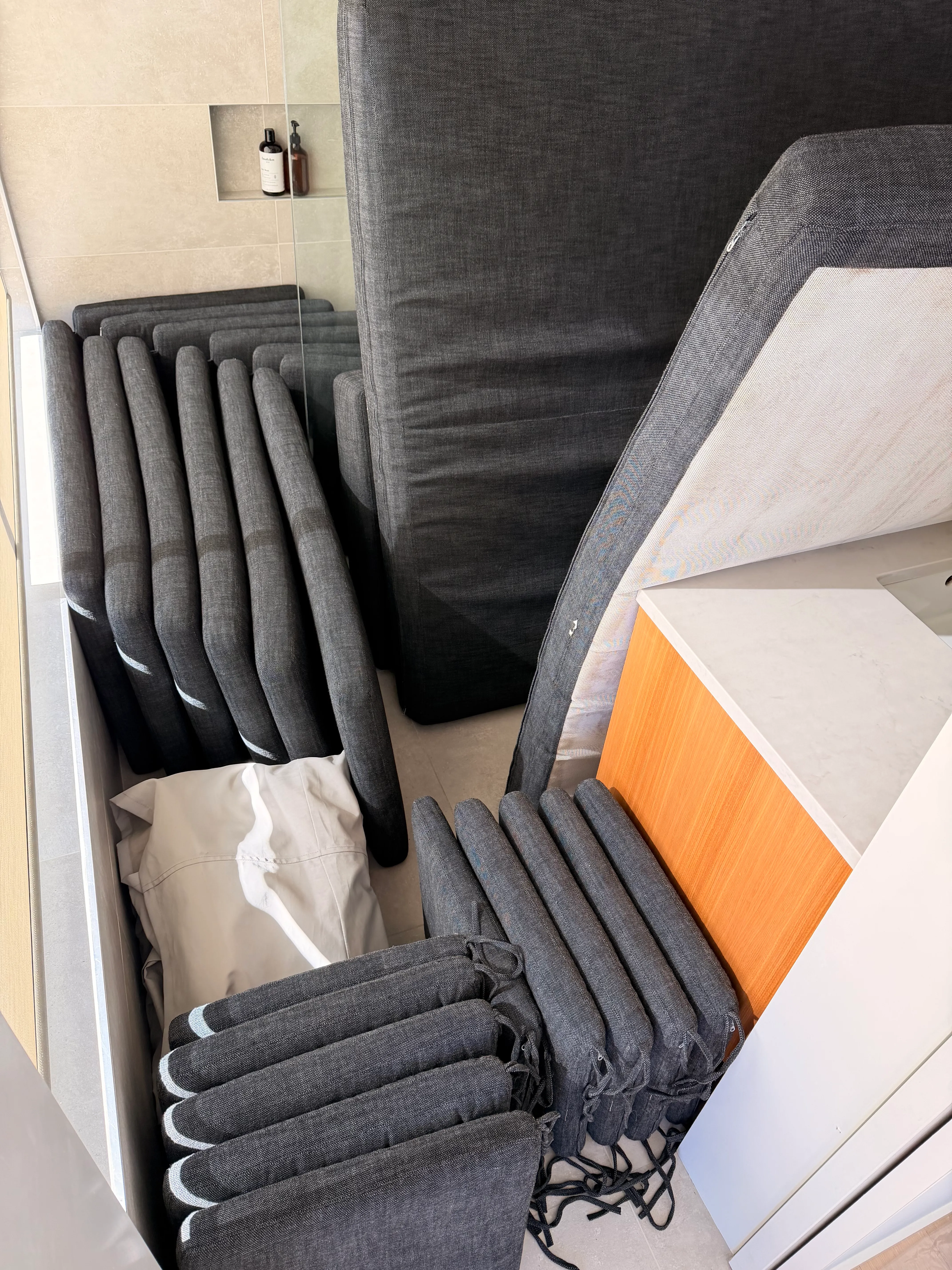 Outdoor cushions and a lounger pad stacked indoors, put away for the season.