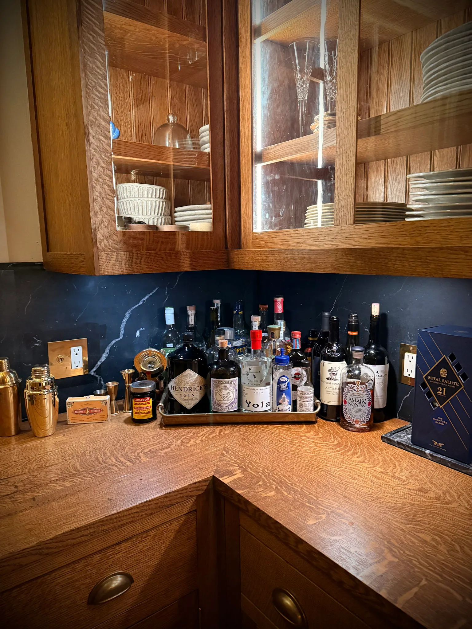 A kitchen bar lined with liquor and spirits bottles, including champagne and a premium gin set.